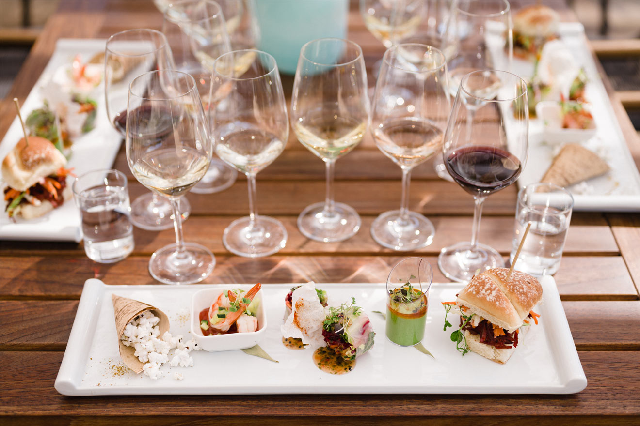 food and wine pairings set up on a table, small dishes and multiple vines in a vine glasses